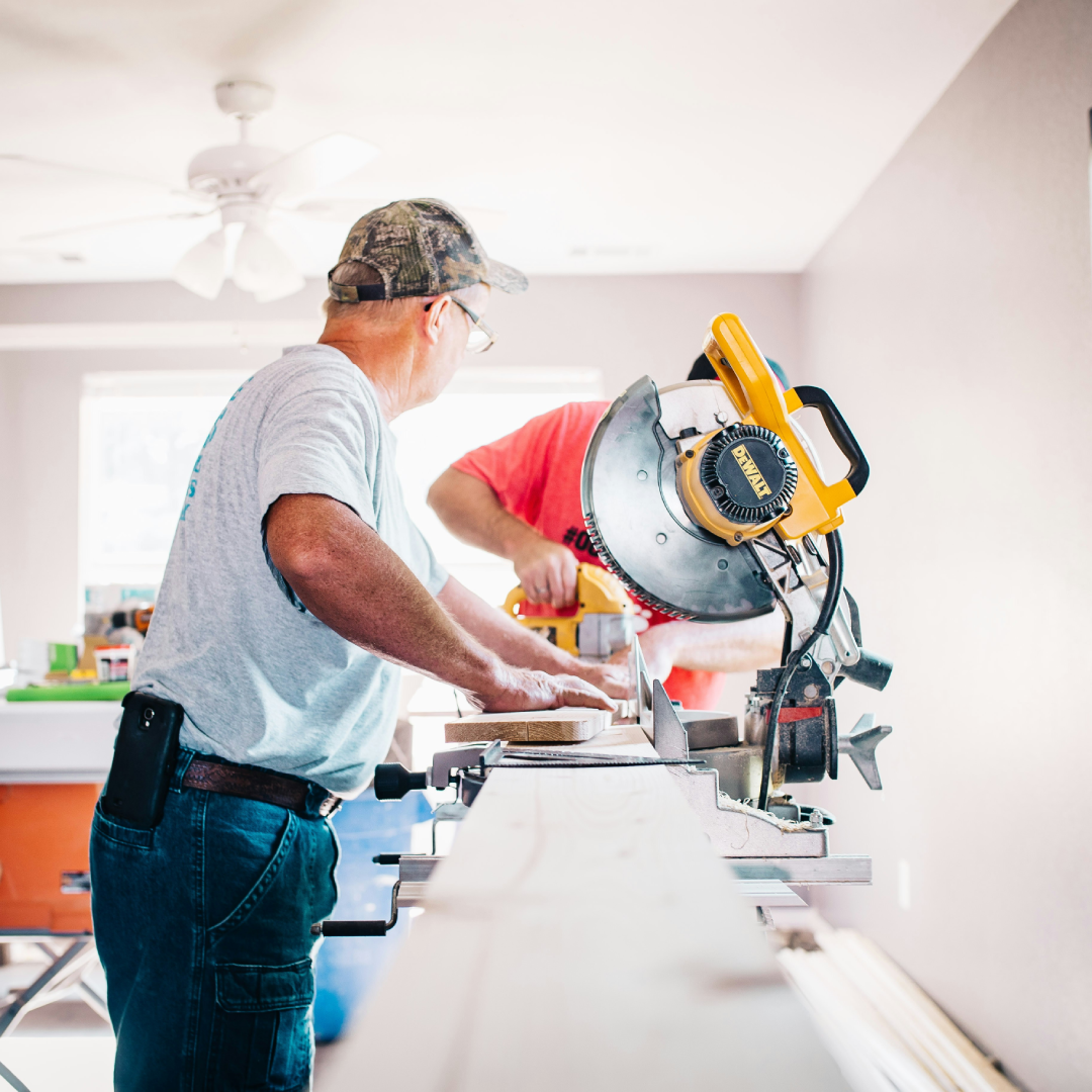 Two workers using a circular saw to cut wood during a home renovation project.