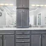 A modern bathroom featuring gray cabinets and elegant marble countertops, showcasing a sleek and sophisticated design.