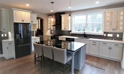 A modern kitchen featuring sleek white cabinets paired with elegant black countertops.