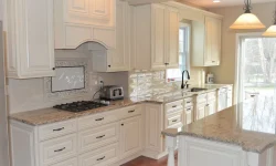 A modern kitchen featuring white cabinets and elegant granite countertops, showcasing a clean and stylish design.